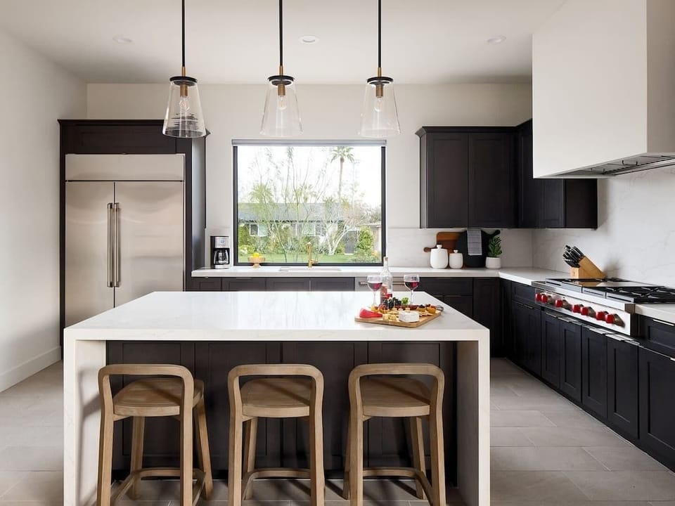 (1st Floor) Fully equipped kitchen with stainless steel appliances, cooking essentials, and kitchen island bar seating.