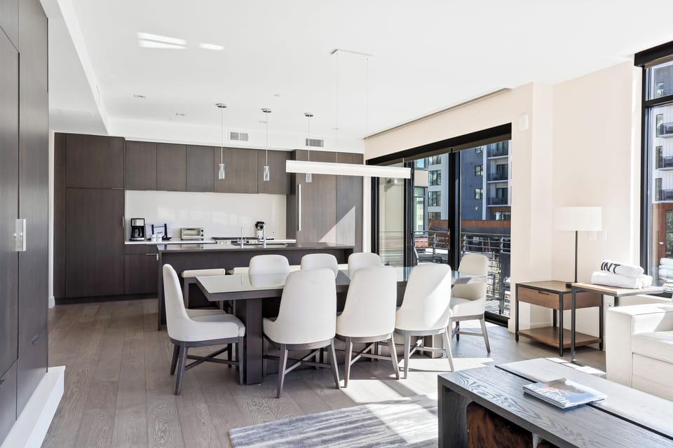 - Open concept dining and kitchen with seating for large gatherings  
- Modern wood cabinetry and sleek island with bar stools included  
- Floor to ceiling windows bring natural light and resort views in