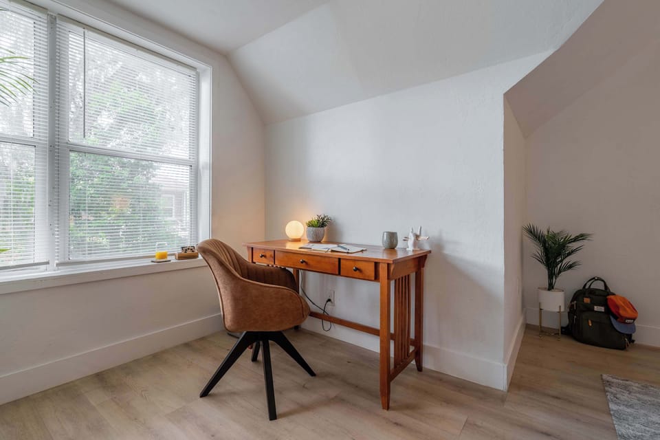 Find your focus in a space designed for clarity. This minimalist workspace combines warm wood tones with thoughtful accents like a glowing orb lamp and potted greenery.