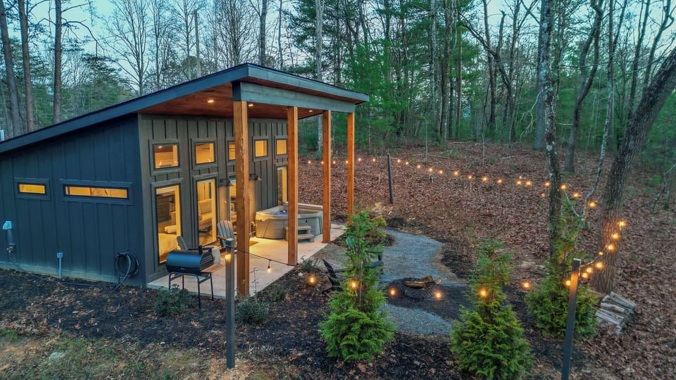 Exterior at dusk. Remote control string lights surround the cabin.