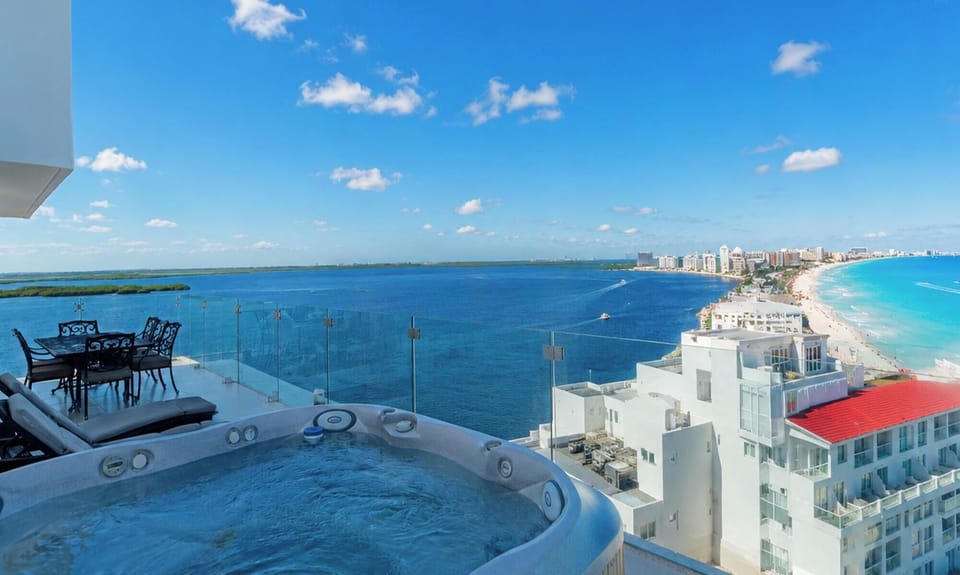 #323 - Penthouse Combo - 8 bedrooms, 6 baths sleeps 18 Top-floor balcony with bubbling hot tub, black wrought-iron dining set, and panoramic ocean and coastline views.
