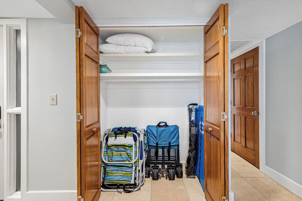 Large storage closet with beach equipment, including 4 beach chairs and a cart for guest use