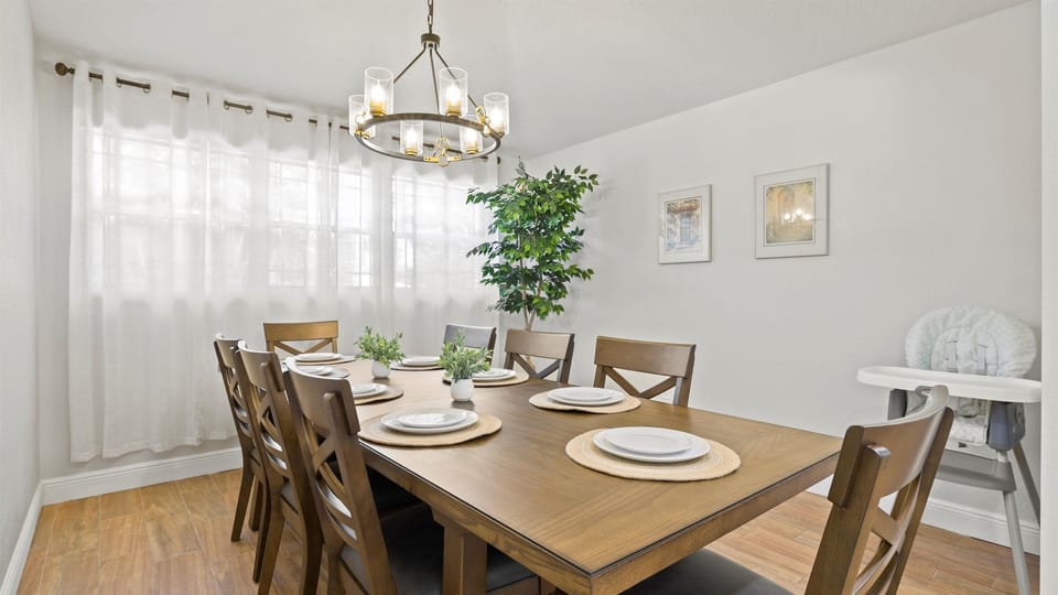 Spacious dining area with seating for eight, warm natural light, and a high chair for little ones—perfect for family meals and group gatherings.