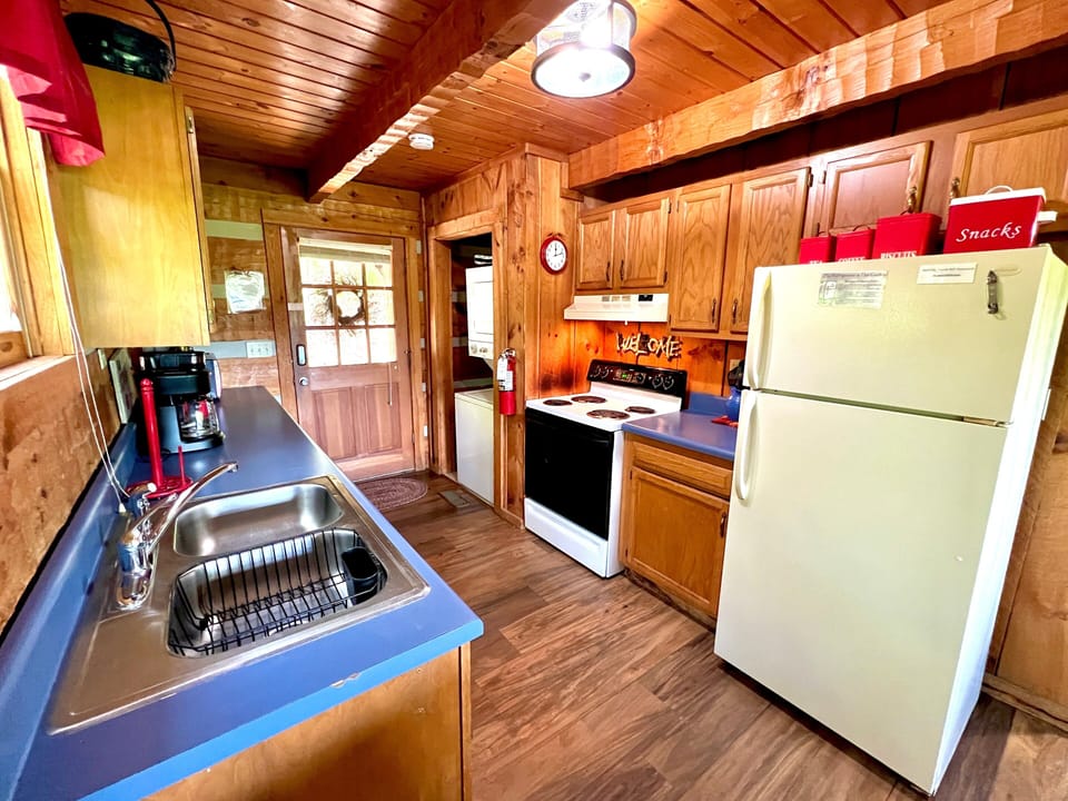 Kitchen with full size refrigerator, stove, sink, and wood cabinet storage at Bearadise Found rustic cabin rental in Pigeon Forge, Tennessee