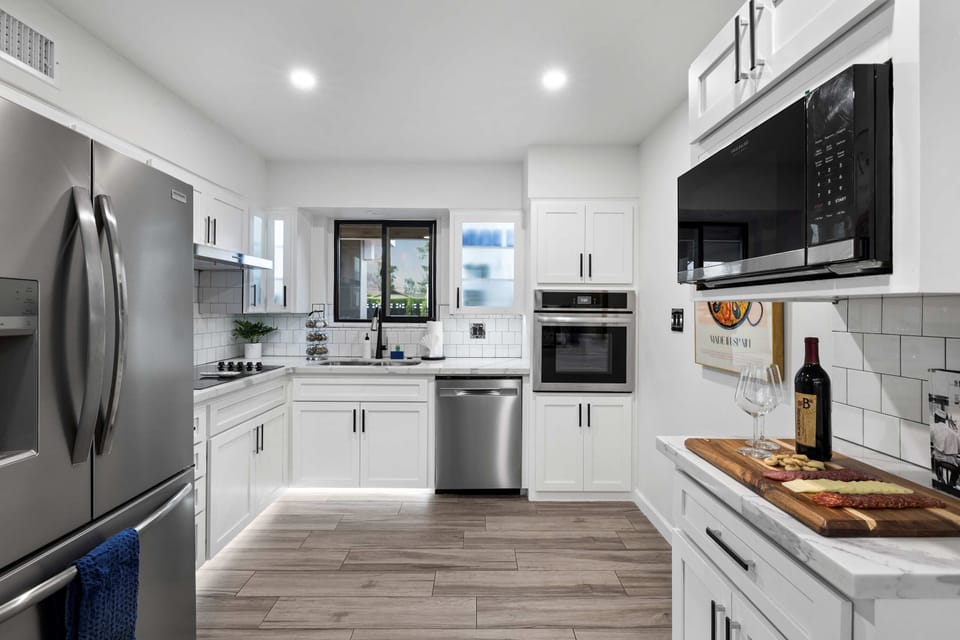Well appointed kitchen featuring stainless steel appliances, white cabinetry, and wood flooring, perfect for culinary adventures.