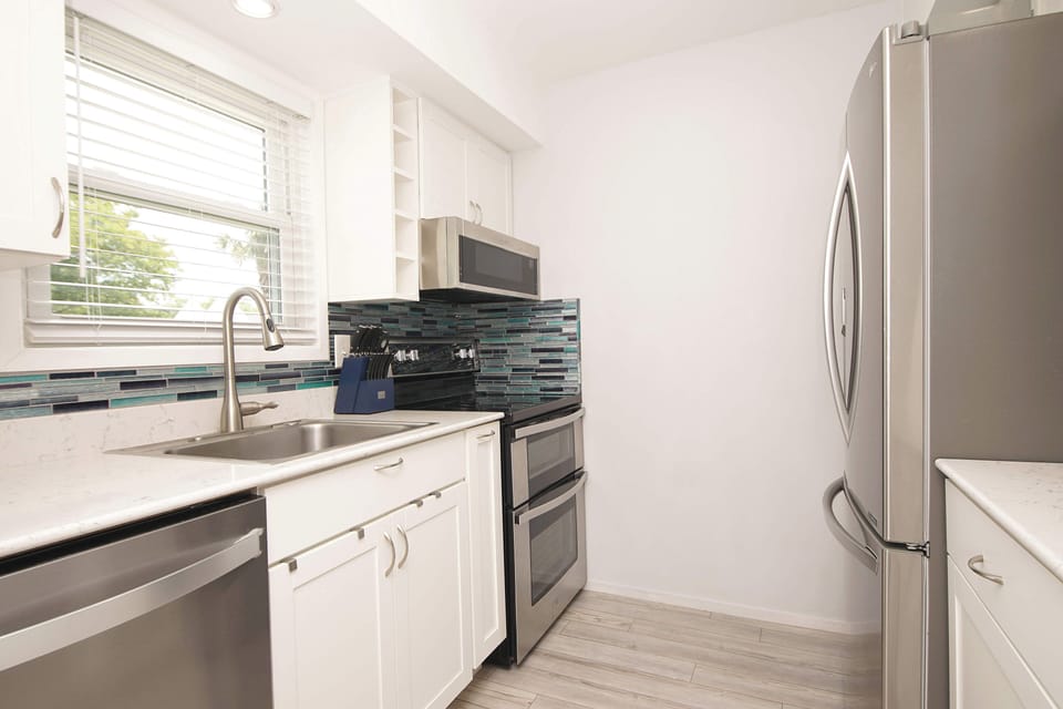 Your modern kitchen features stainless steel appliances, quartz countertops, and a vibrant mosaic backsplash for culinary adventures.