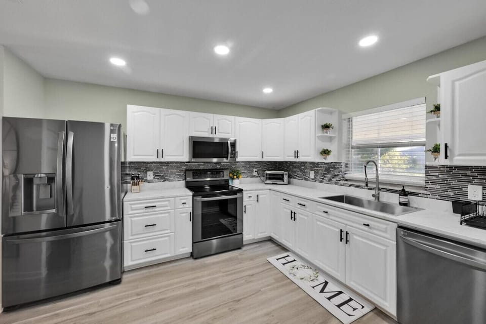 Modern kitchen with sleek stainless steel appliances, white cabinets, and stylish backsplash.