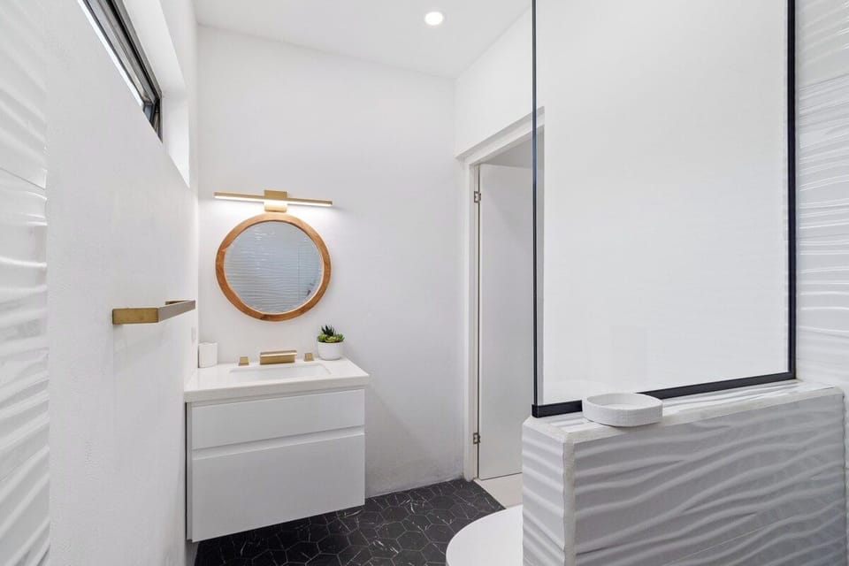 - Lavish bathroom of the home in Oranjestad Aruba
- Chic vanity with upscale lighting and stylish round shape mirror
- Walk-in shower area