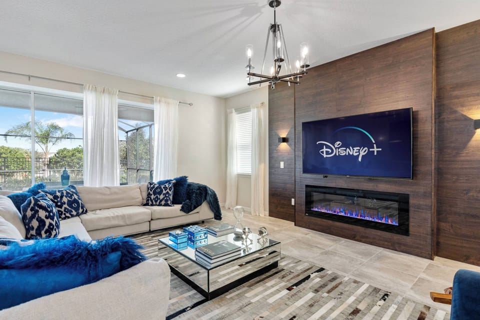 Relax in the bright and airy living room featuring a stylish sectional sofa with plush blue accents. The sleek coffee table on a textured rug pairs beautifully with the modern fireplace, creating a warm ambiance for cozy evenings.