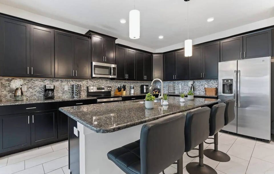 This stylish kitchen, with rich dark cabinetry and sleek granite countertops, offers a sophisticated atmosphere for meal prep. The modern bar stools invite casual gatherings, and the tile flooring adds contemporary charm.