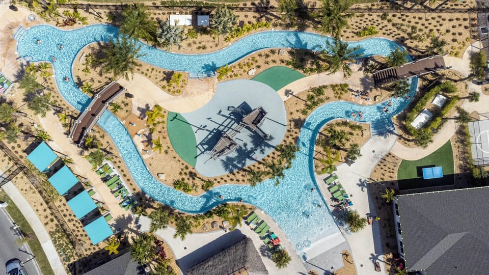 Take in the breathtaking aerial view of our expansive pool area, featuring winding waterways and lush greenery. Relax in the sun-drenched spaces and comfortable lounge chairs for an inviting atmosphere perfect for unwinding.