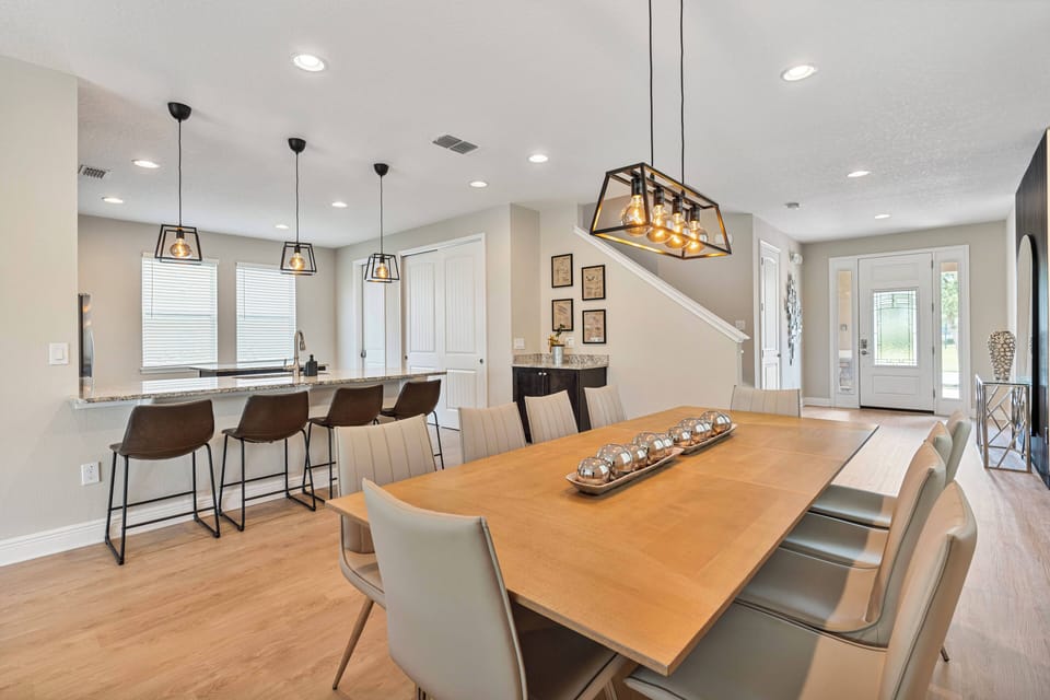 Enjoy the natural light flooding this stylish dining area, where a sleek wooden table invites gatherings. Modern pendant lights and chic bar stools elevate the ambiance, ensuring every meal is a memorable experience.