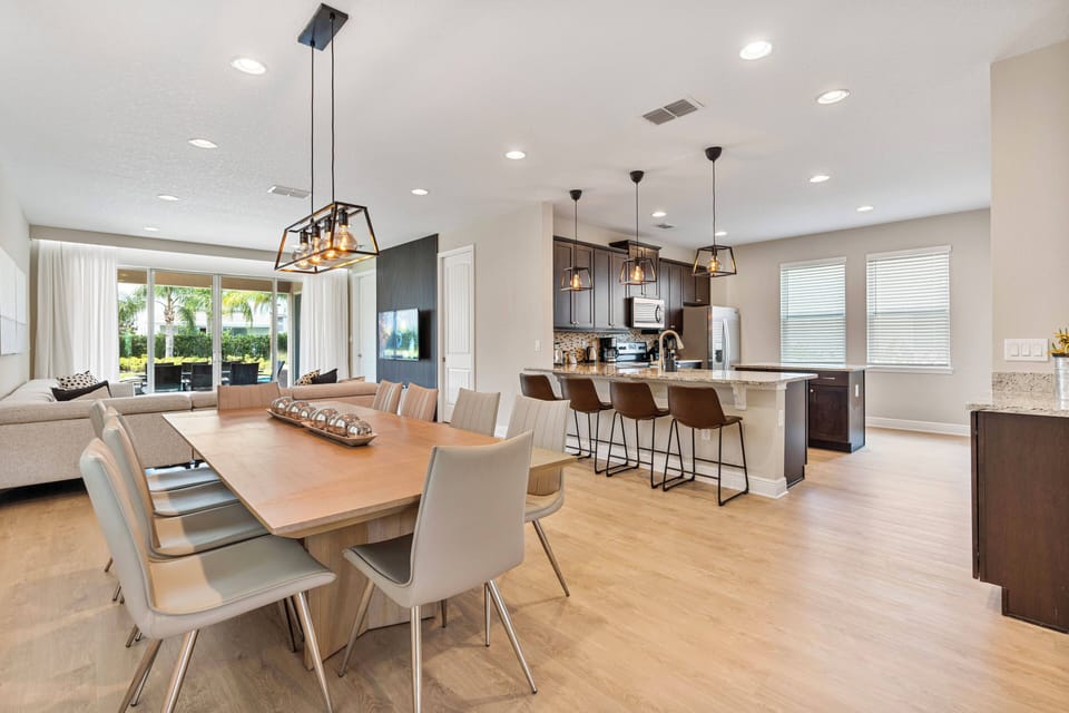 Enjoy a stylish dining area with a sleek wooden table and modern chairs, ideal for gatherings. The open layout lets in natural light, showcasing the elegant cabinetry and contemporary fixtures in the adjoining kitchen.
