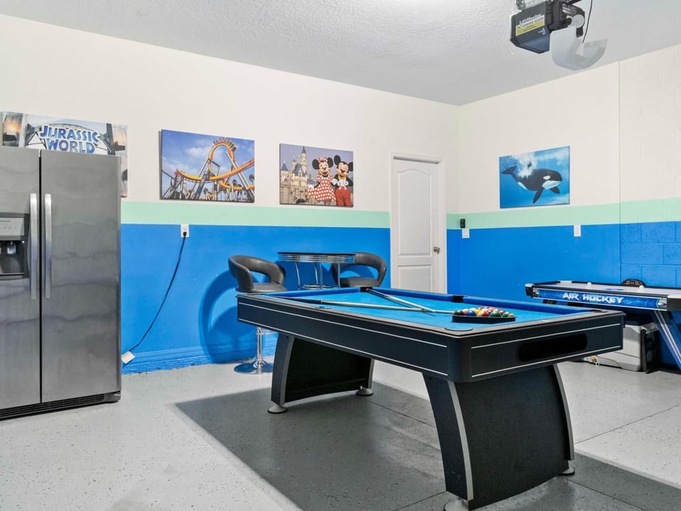 Fun-filled game garage with pool table, air hockey, bar seating, and a full fridge.