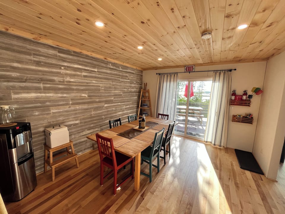 Bright dining area with colorful chairs, a sturdy wooden table, and direct access to the outdoor deck through sliding glass doors, perfect for enjoying meals with a view.