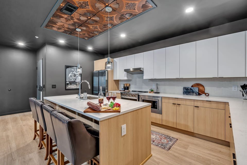 The fully equipped modern kitchen features culinary essentials, stainless steel appliances, and island bar seating.