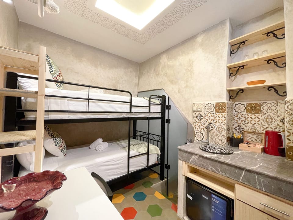 A studio equipped with two comfortable beds, a fully equipped kitchen, and a private desk.