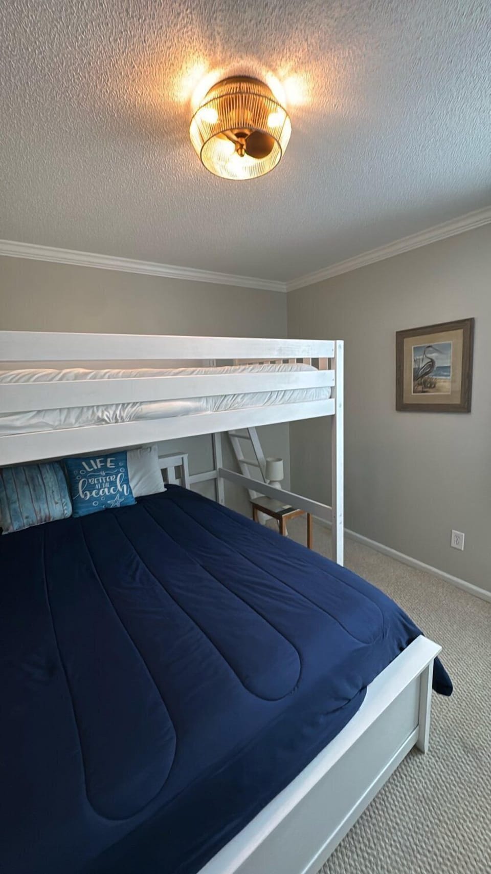 Your coastal-themed retreat features a classic bunk bed setup with a crisp white frame and inviting navy blue bedding, perfect for cozy nights after beachside adventures.