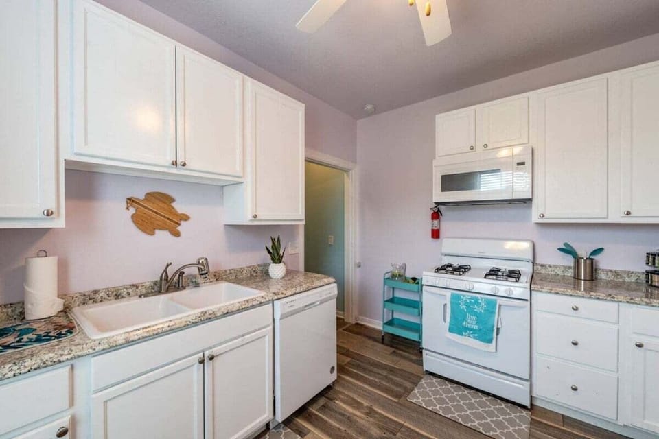 Fully equipped kitchen with granite countertops, white cabinetry, stainless sink, and spacious cooking area for vacation rental guests.