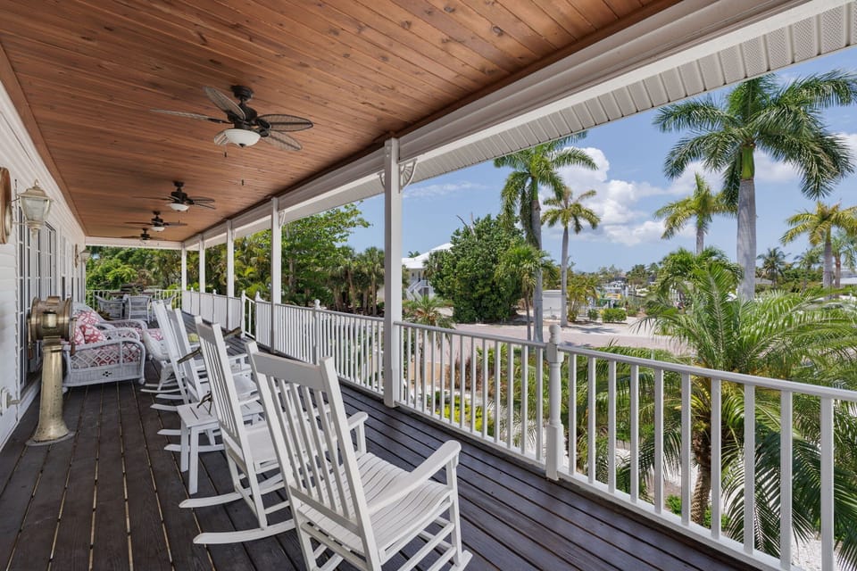 Expansive balcony features rocking chairs, an outdoor sofa, and dining table where guests can enjoy the incredible sea breeze as it rolls in off the bay and into your home