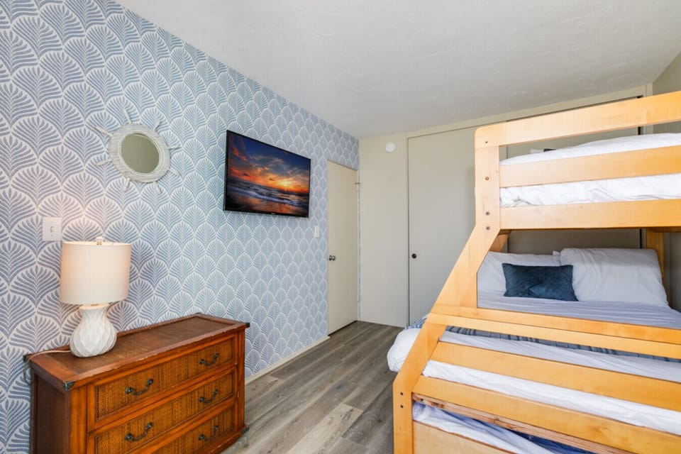 This charming room features a bunk bed set against a beautifully patterned accent wall that sleeps 4