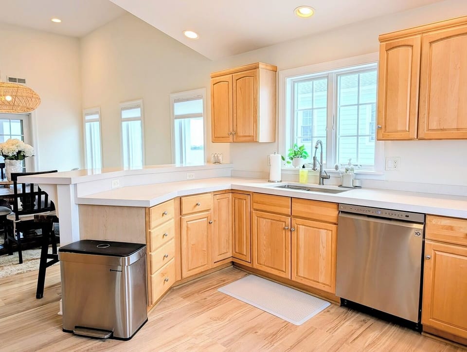 33 Inlet View North Bethany Beach Kitchen - A kitchen featuring light wood cabinetry, a stainless steel dishwasher, and an open layout that overlooks the adjacent dining area.