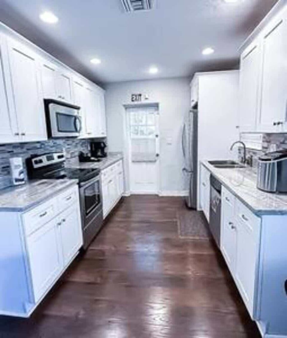 Fully equipped modern kitchen featuring stainless steel appliances, sleek white cabinetry, and a stylish tile backsplash. With plenty of counter space and all essential cookware provided, it's perfect for preparing delicious meals during your stay.