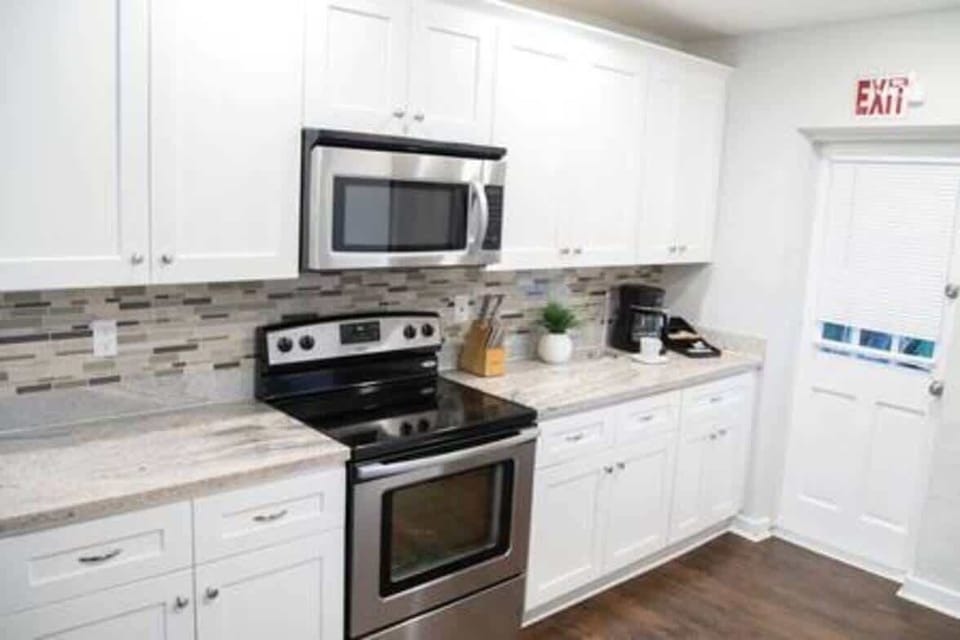 Fully equipped modern kitchen featuring stainless steel appliances, sleek white cabinetry, and a stylish tile backsplash. With plenty of counter space and all essential cookware provided, it's perfect for preparing delicious meals during your stay.