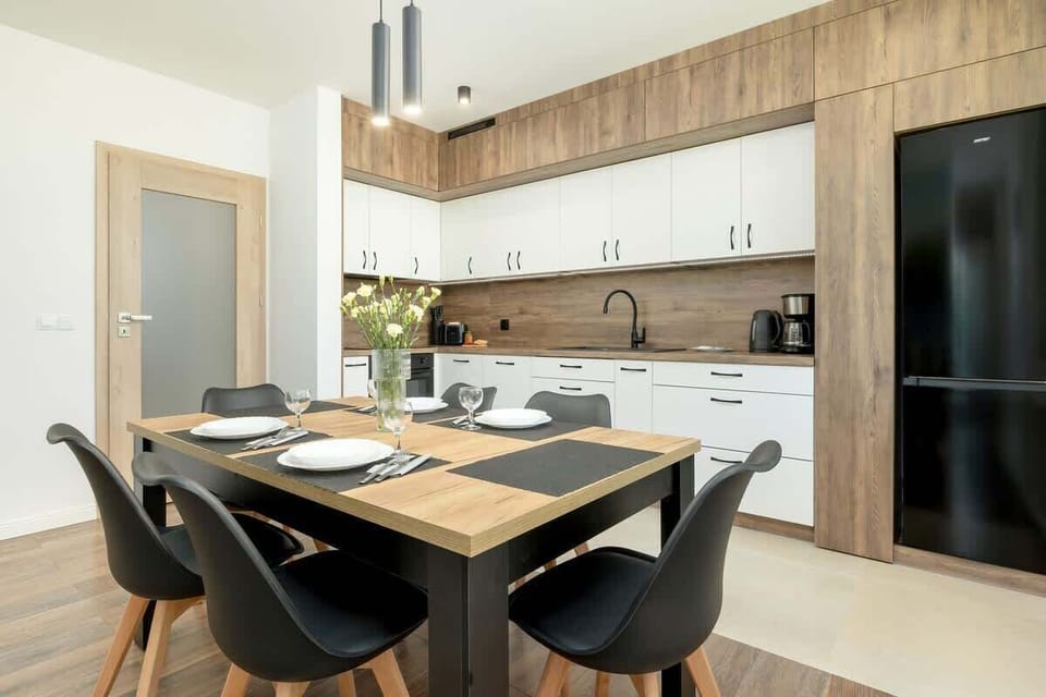 A kitchenette with white cabinets, modern appliances, and a wooden countertop combines functionality with aesthetics.