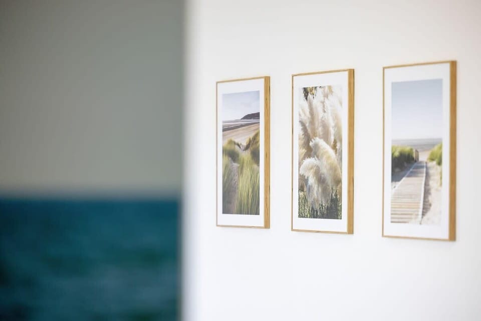 A section of the living room with three elegant framed pictures hanging on a white wall adds subtle character and decorative charm to the interior.