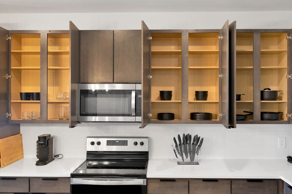Modern kitchen with sleek stainless steel appliances and neatly arranged utensils, perfect for effortless cooking during your short-term rental stay.