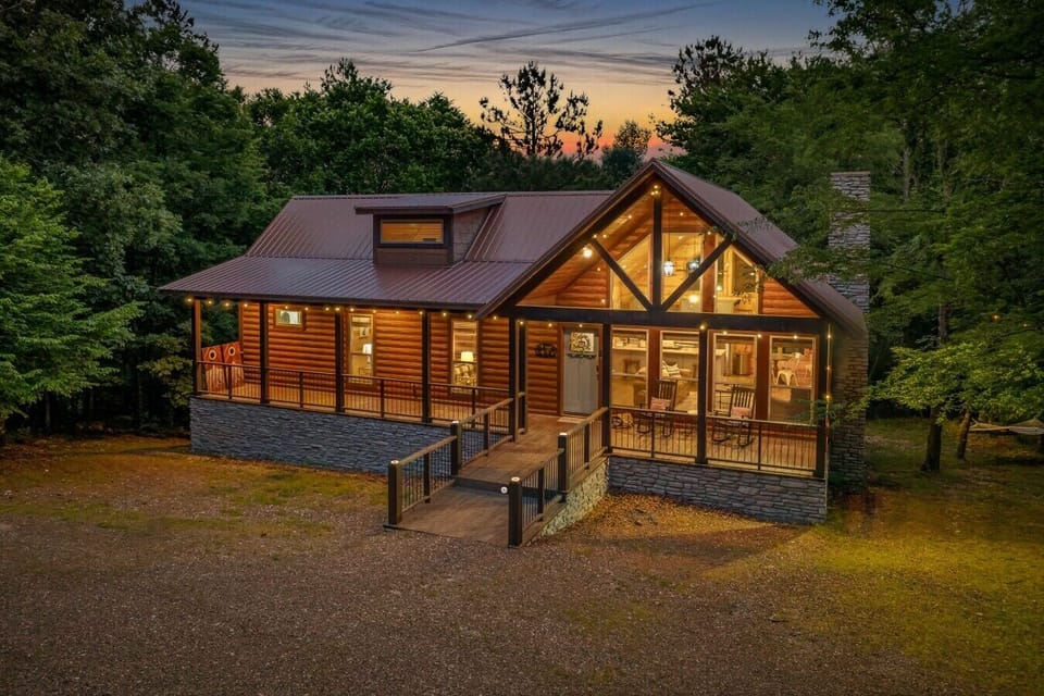 Twilight Pines exterior at golden hour — warm A-frame facade with timber framing and string lights.