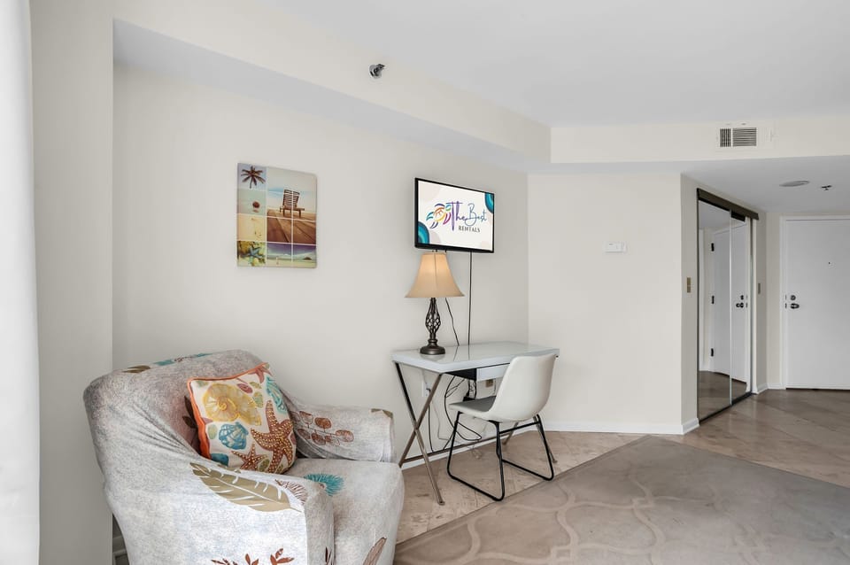 Unwind in your modern living space with comfortable seating, work desk, and flat-screen TV for perfect relaxation or productivity.