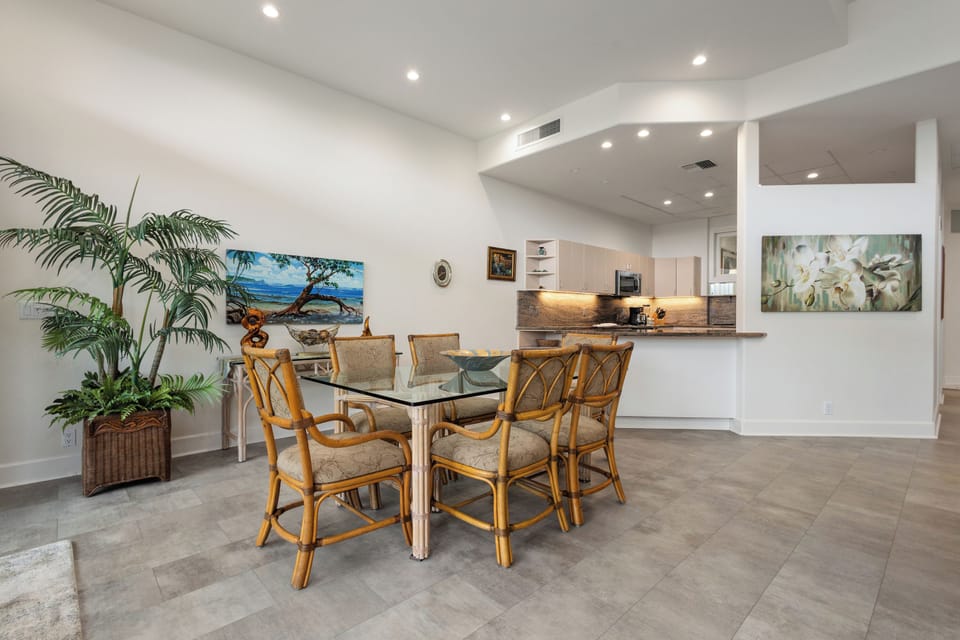 Step into your open-concept dining and kitchen area where tropical touches and coastal art create a welcoming atmosphere for shared meals and easy conversation.