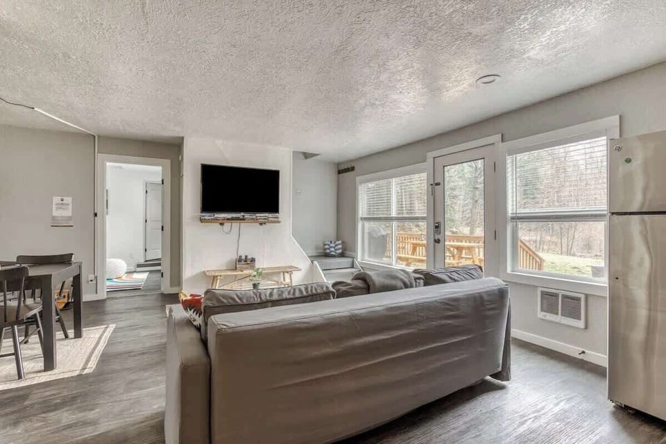 Cozy living room with forest views, comfy seating, and direct access to the deck—perfect for relaxing or movie nights.