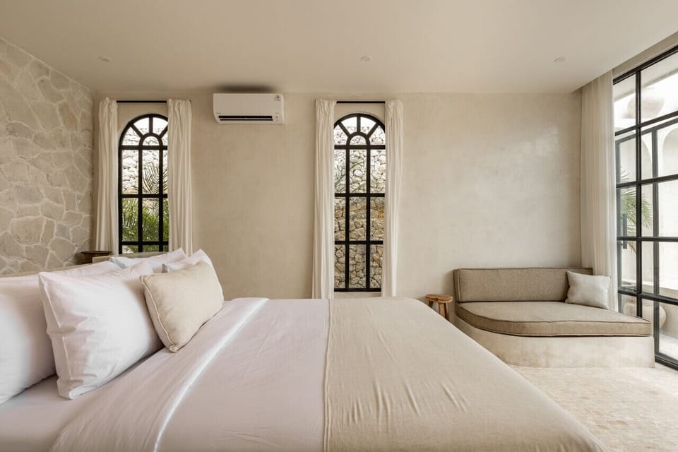 An airy bedroom sanctuary with plush linens and a serene view, embodying modern luxury with a touch of the traditional.