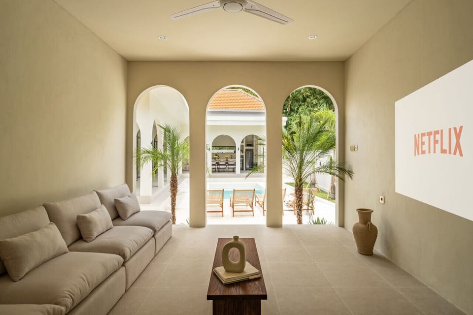 A stylish lounge with a view of the pool, framed by classic archways and lush palms, perfect for both relaxation and entertainment.