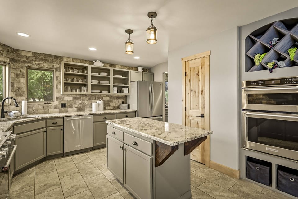Huge kitchen has two built in ovens, separate gas range/oven, and pantry next to a center island. Chefs kiss!