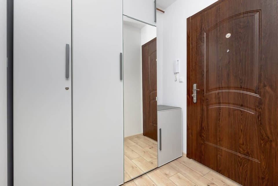 The hallway with white cabinets and a wooden door creates a tidy and bright entrance area.