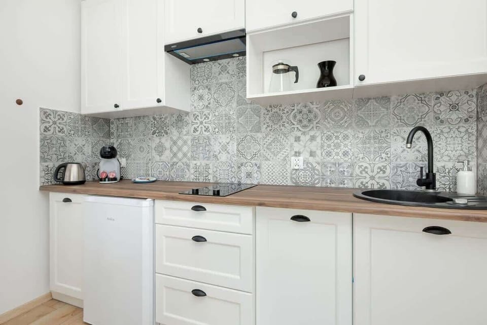 A modern kitchenette with white cabinets and silver appliances blends perfectly with the bright interior design.
