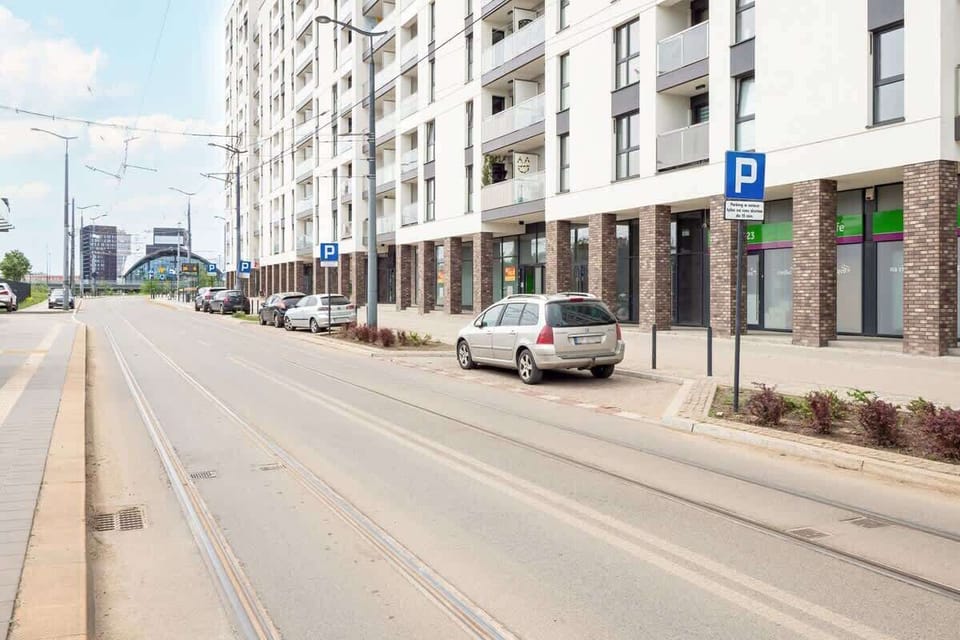 The view of the street with tram tracks and contemporary architecture highlights the apartment’s convenient location in a modern part of the city.