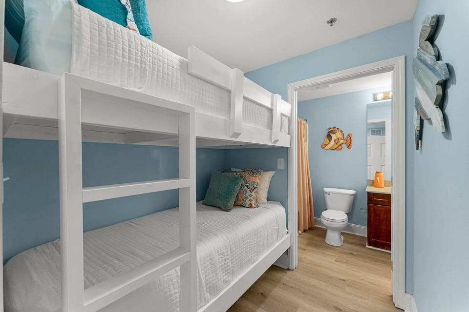 Cozy bunk bed room with direct access to a bathroom featuring a playful fish wall decoration.