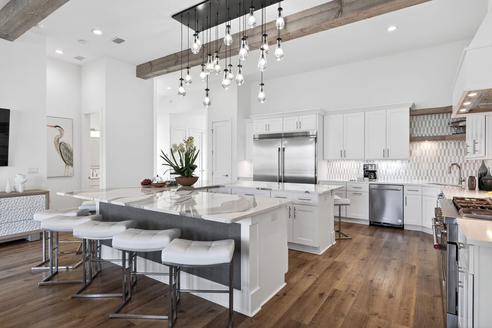 Sleek chef’s kitchen with a massive marble island, designer lighting, and plenty of seating for easy group meals and mingling.