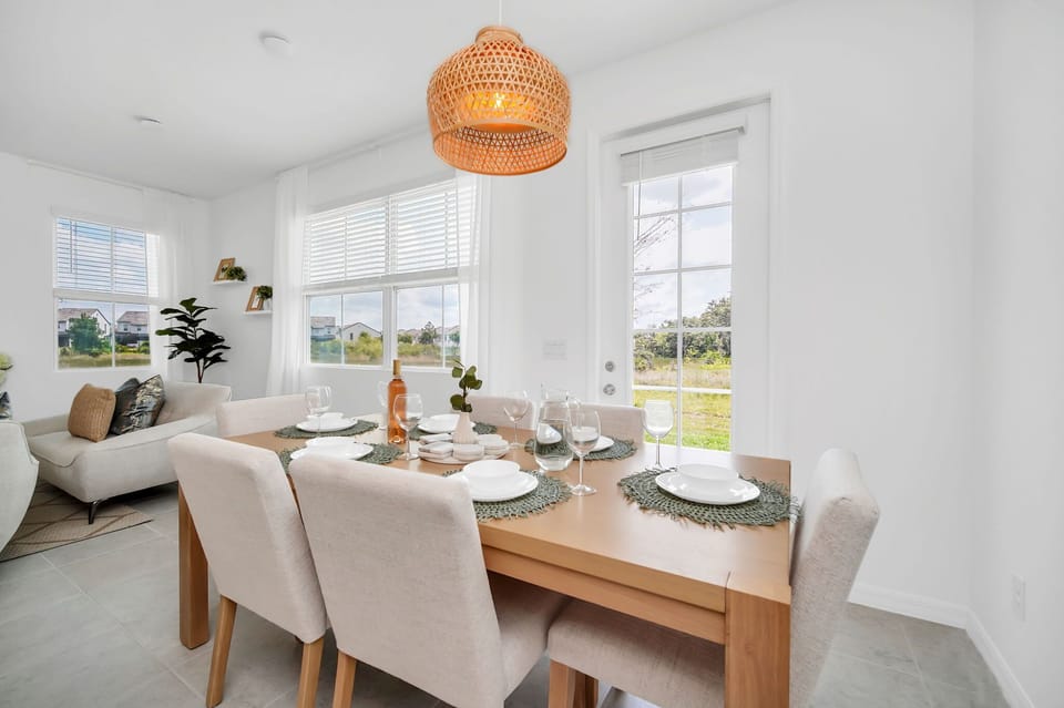 Dining area with natural light and a woven pendant light above the table set for six.