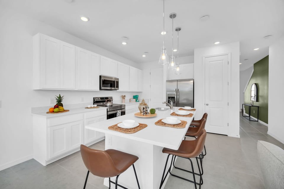 Modern kitchen with white cabinetry, stainless steel appliances, and a breakfast bar with seating for four.