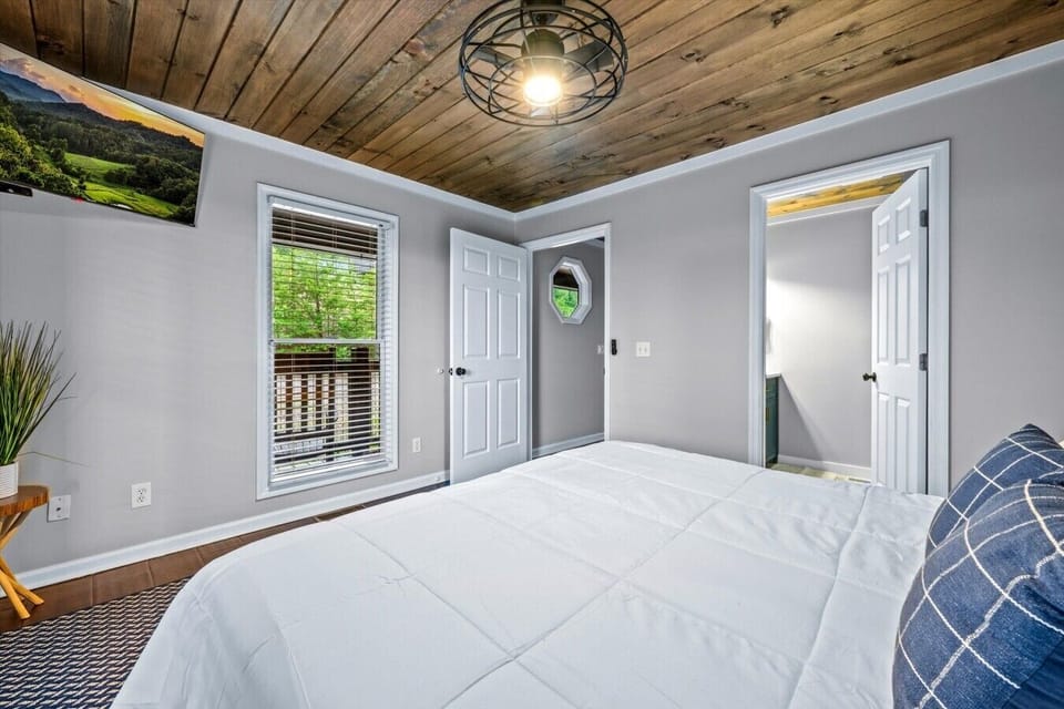 The guest bedroom on the main level includes a king-sized bed, smart TV, and attached full bathroom with a shower..