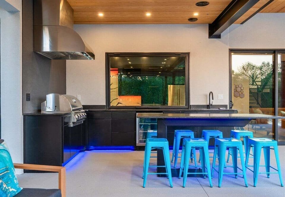 This stylish outdoor kitchen and bar area is perfect for hosting gatherings and enjoying al fresco dining.