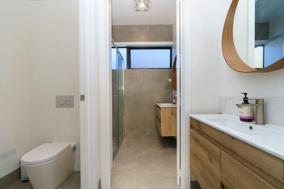 Experience modern elegance in this bathroom, showcasing a sleek walk-in shower, contemporary fixtures, and generous counter space. The stylish design and thoughtful layout ensure a comfortable and refreshing space for your daily routines.