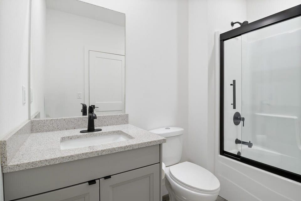 Modern bathroom with quartz vanity, contemporary fixtures, and glass-enclosed shower
