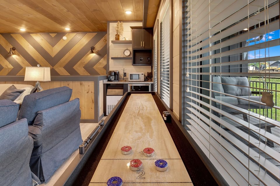Indoor shuffleboard table next to a cozy seating area with natural wood accents.